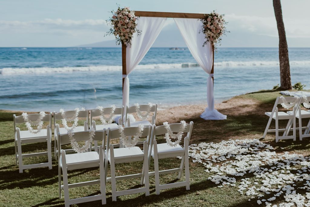 Detail shot of white folding chairs and white curtain arch on the beach for outdoor Ceremony