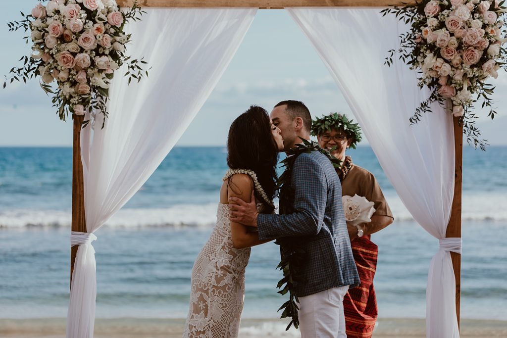 Bride and Groom kissing each others cheeks for outdoor beach Ceremony