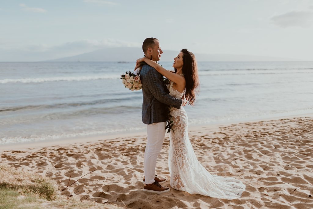 Bride and Groom holding each other close on the shoreline of the beach
