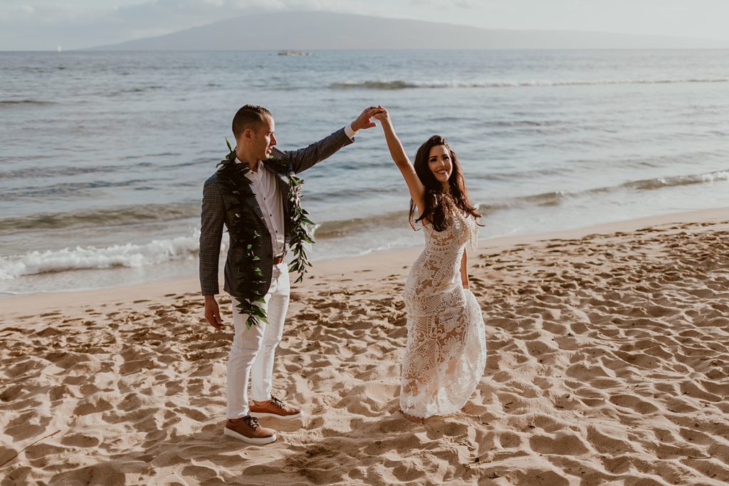 Bride twirling by Groom's hand on the beach