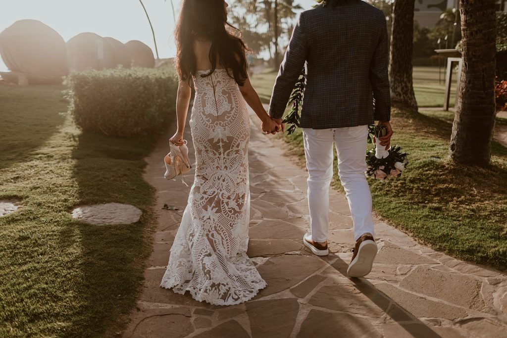 Bride and Groom holding hands and walking on stone sidewalk