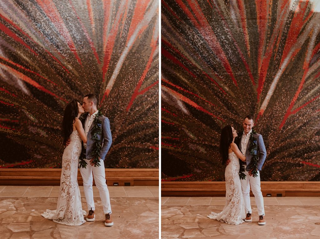 Bride and Groom kissing in front of sparkling leaf painted wall