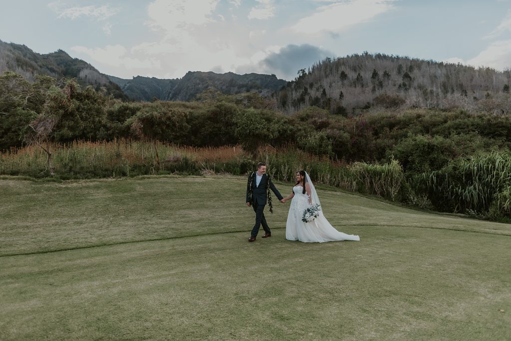 Groom holding Bride's hand walking across golf course