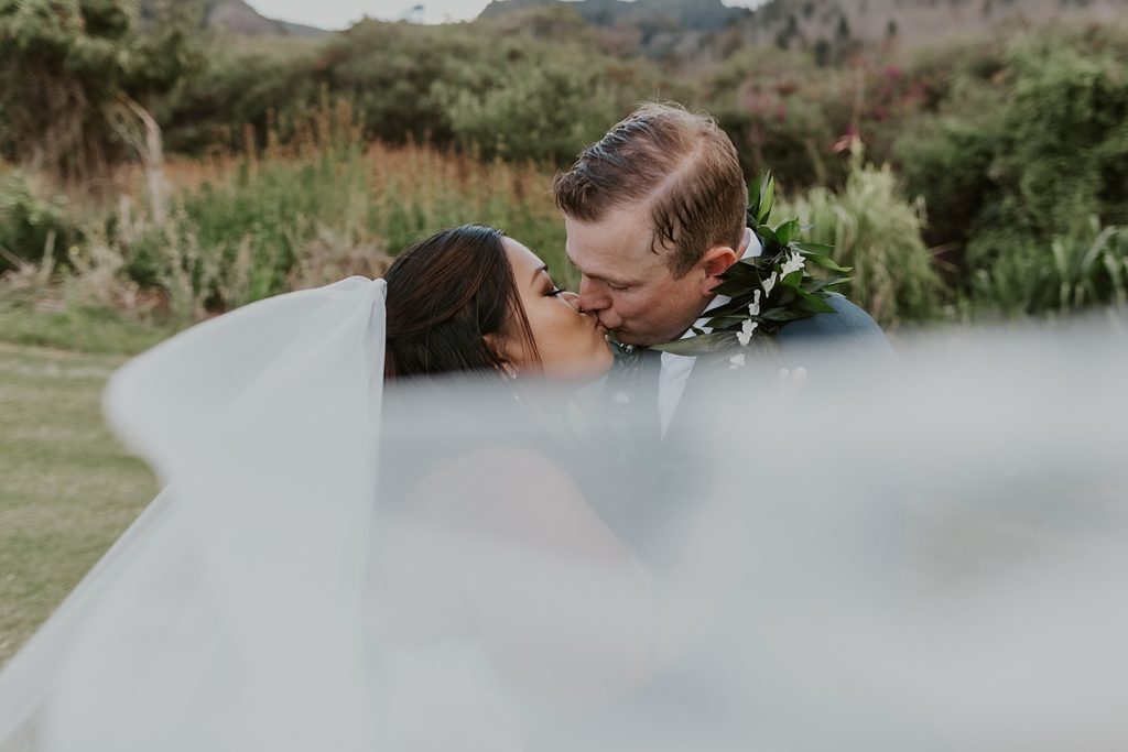 Bride and Groom kissing slightly obscured by flowing veil