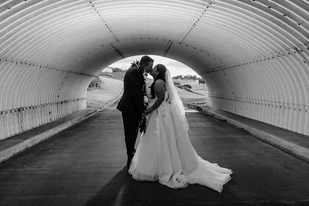 B&W Bride and Groom kissing under tunnel