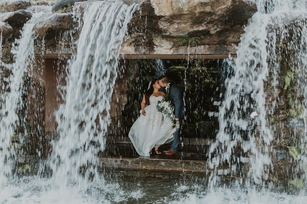 Bride and Groom kissing behind the waterfall