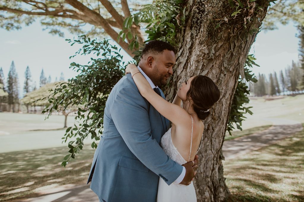 Bride and Groom holding each other next to tree