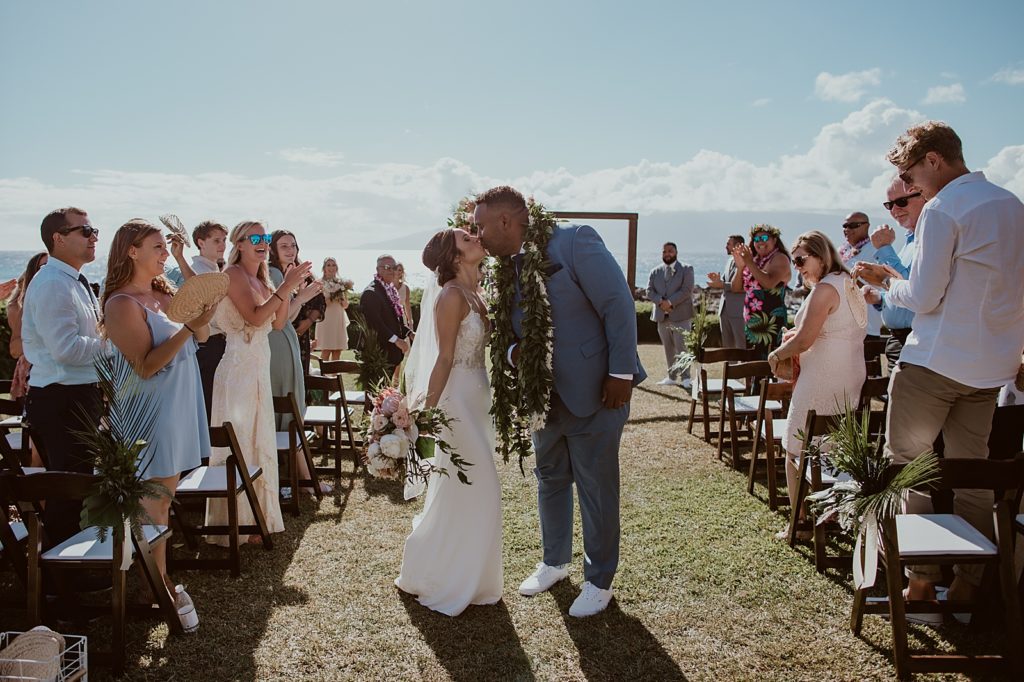 Bride and Groom kissing halfway Ceremony exit with audience clapping