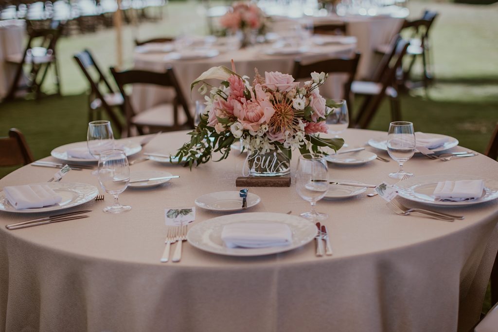 Detail shot of Reception table with silverware and pink tropical flower centerpiece