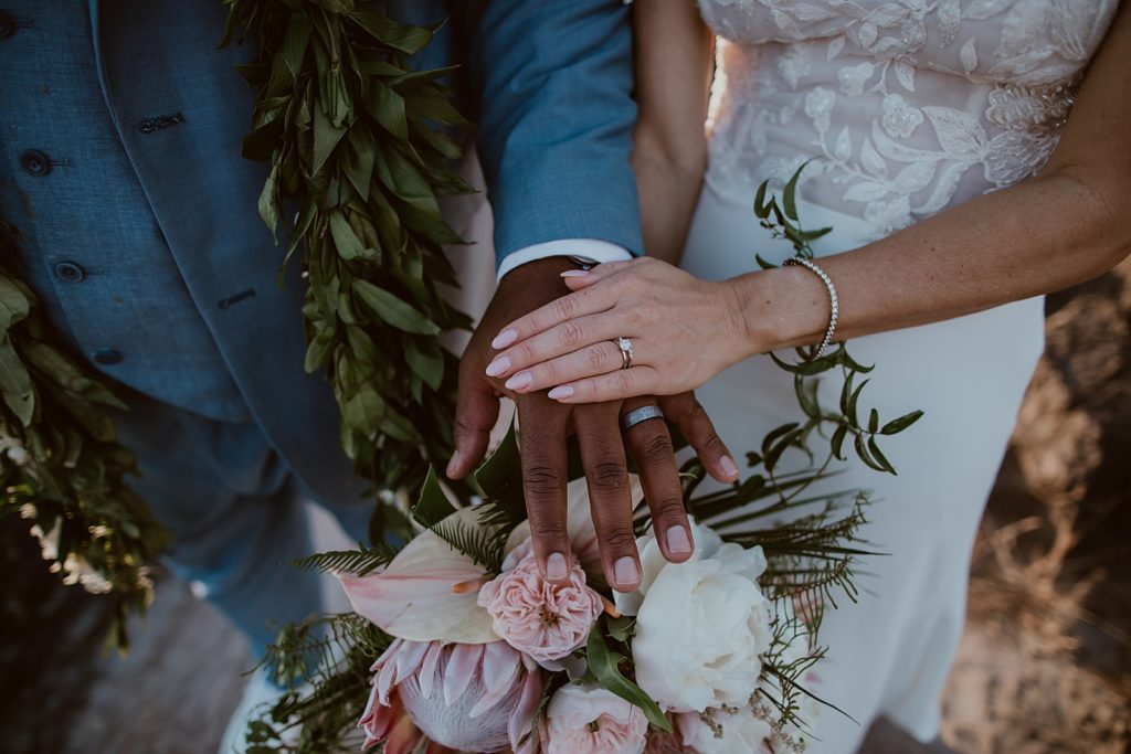 Closeup of Bride and Groom holding hands with wedding bands on