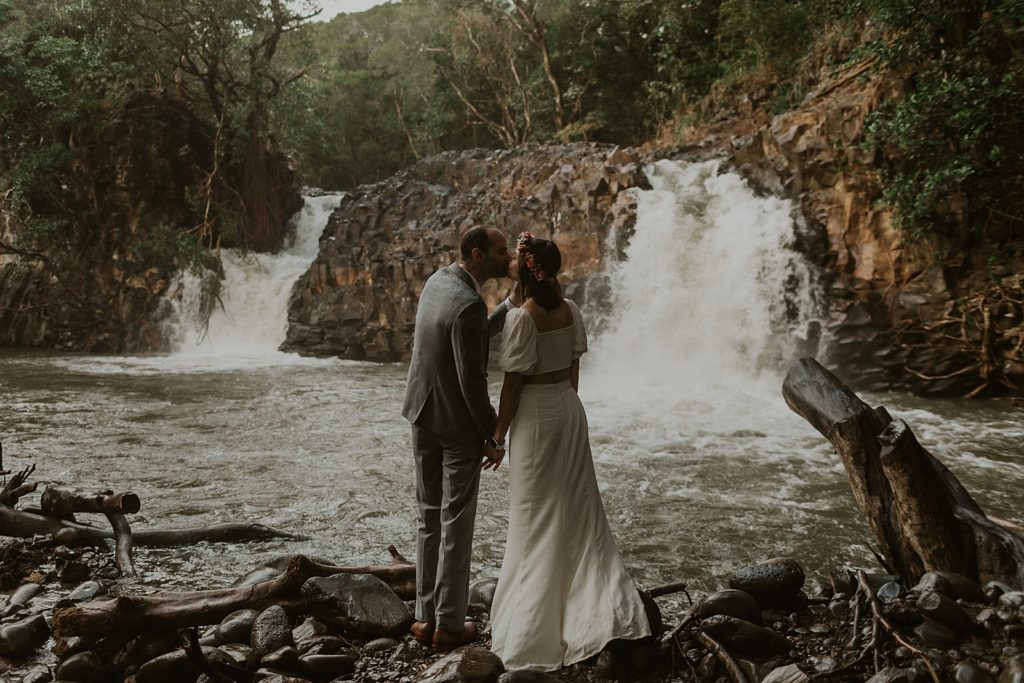 Bride and Groom kissing in front of waterfall