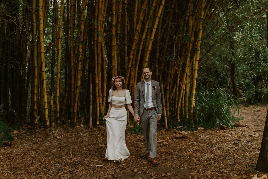 Bride and Groom holding hands and walking in front of bamboo