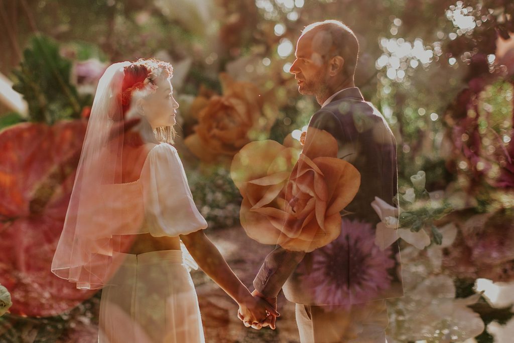 Overlay of Bride and Groom holding hands and looking at each other with colorful flowers