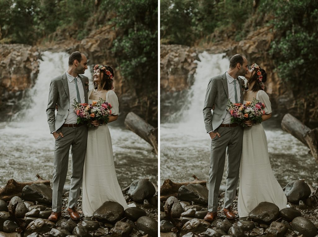 Bride and Groom looking at each other and kissing in front of forest waterfall