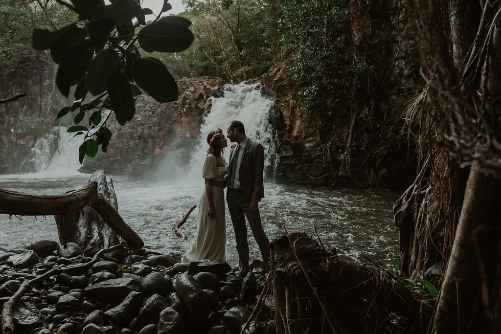 Bride and Groom looking at each other in dark forest with waterfall