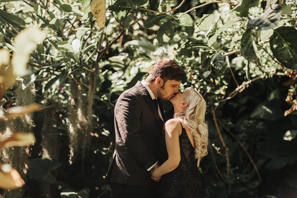 Bride and Groom kissing surrounded by greenery First Look
