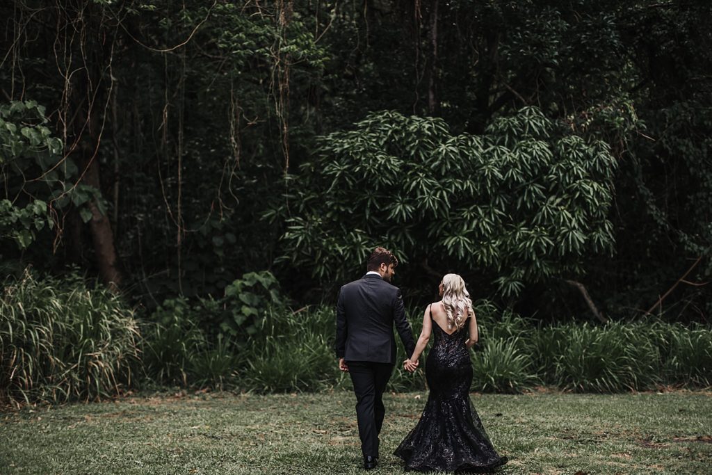 Bride and Groom holding hands about to enter deep green jungle