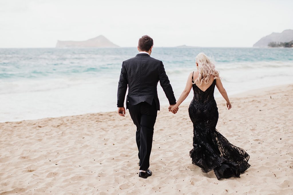 Bride and Groom holding hands and walking on the sand towards the water