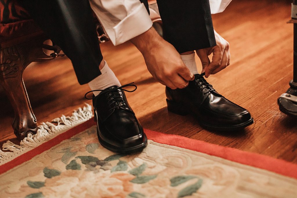 Closeup of Groom tying black leather shoes getting ready