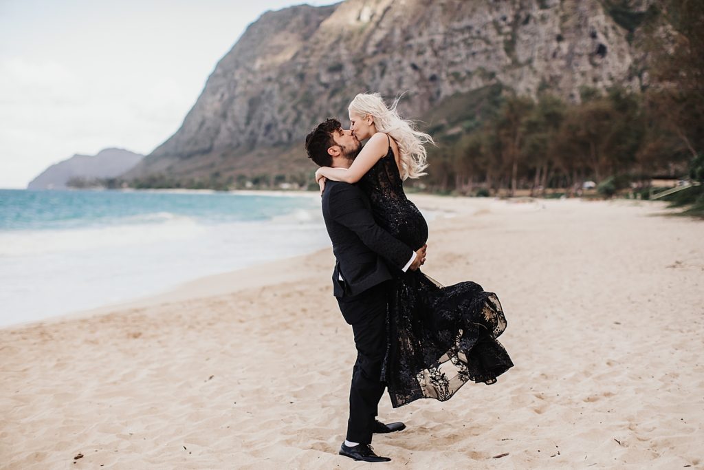 Groom holding Bride up and kissing her on the beach