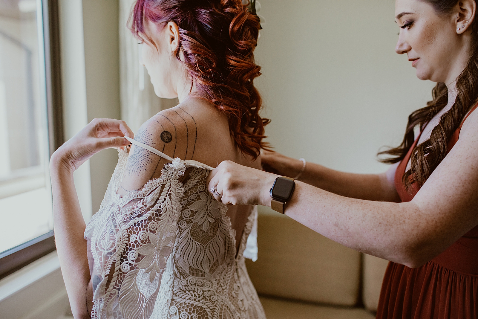 Closeup of Bride getting dress on with help from Bridesmaid