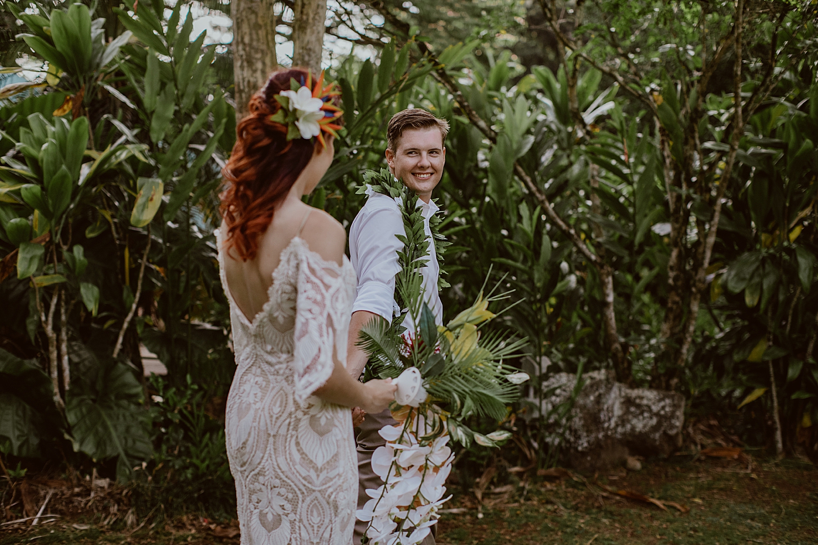 Groom holding Bride's hand and looking at her in tropical forest