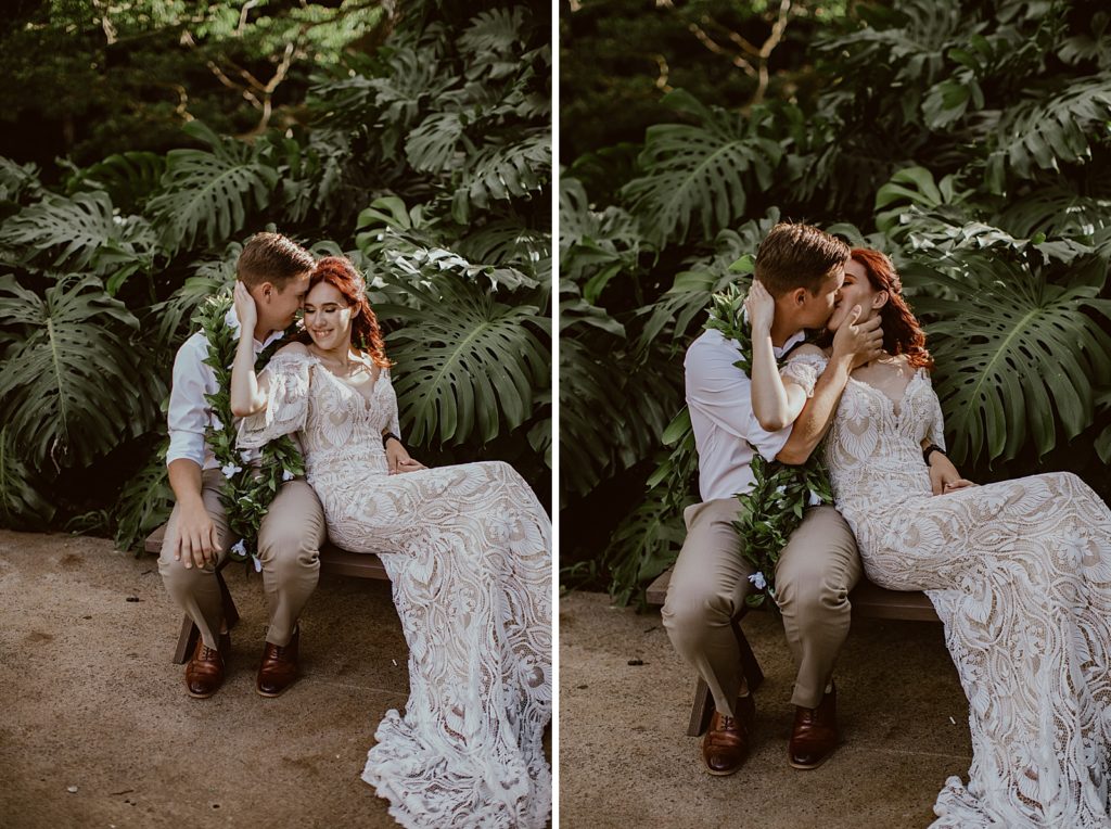 Groom sitting on bench with Bride leaning on him by green plants