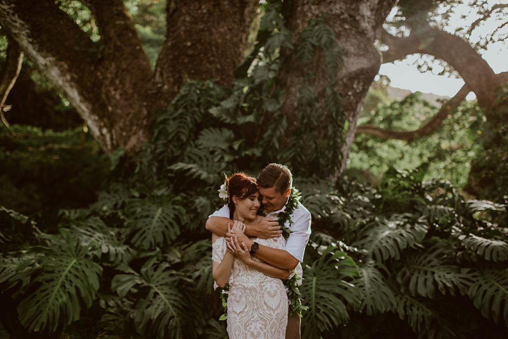 Groom holding Bride from behind in tropical greenery
