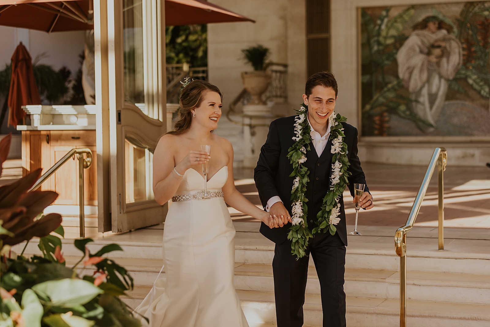 Bride and Groom holding hands and holding a glass of Champaign while walking together