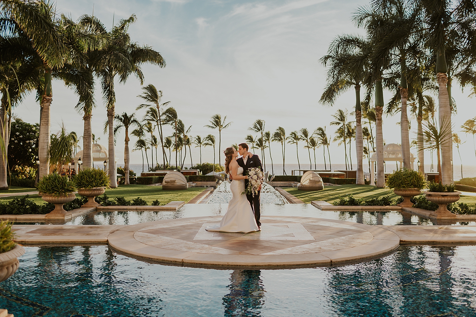 Wide shot of Bride and Groom standing in center of water fountain area