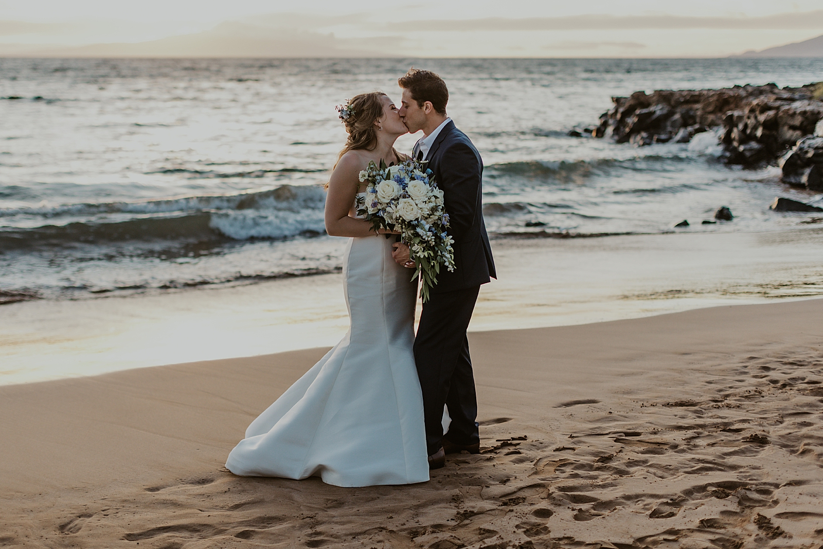 Bride and Groom holding each other and kissing on the beach