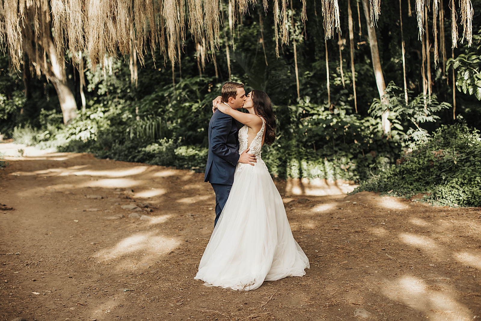 Bride and Groom holding each other and kissing in forest
