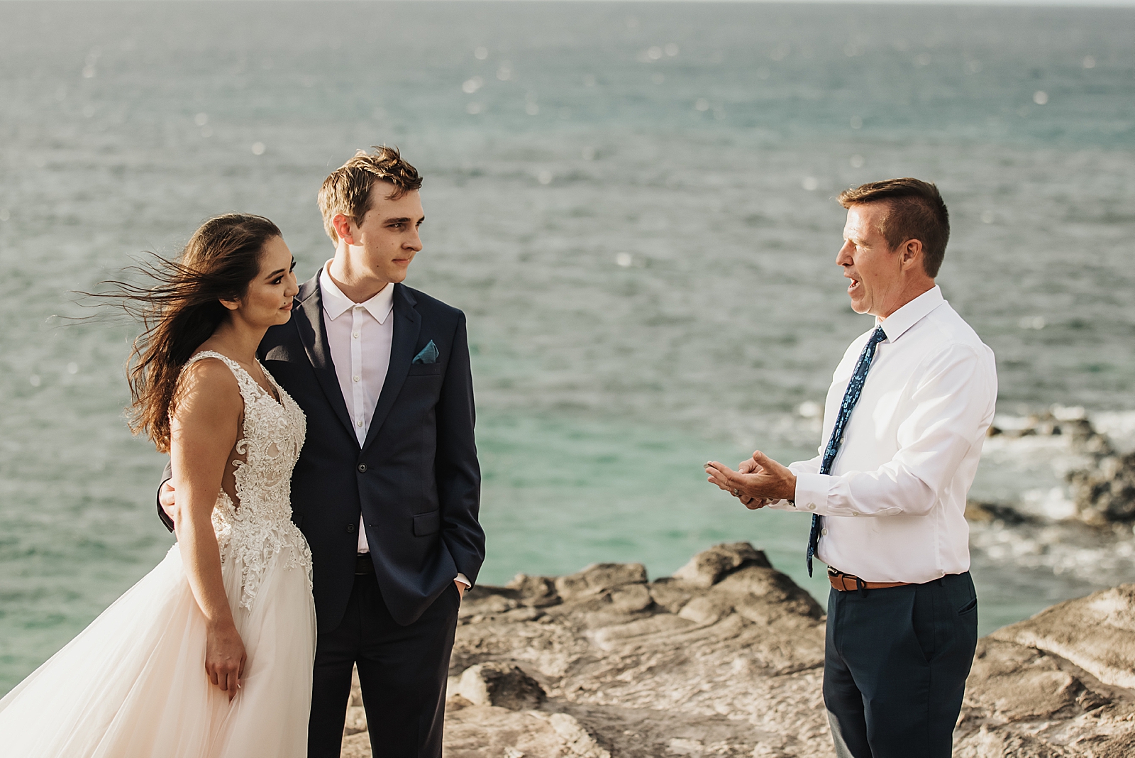 Bride and Groom listening to Officiant for cliffside ocean Elopement
