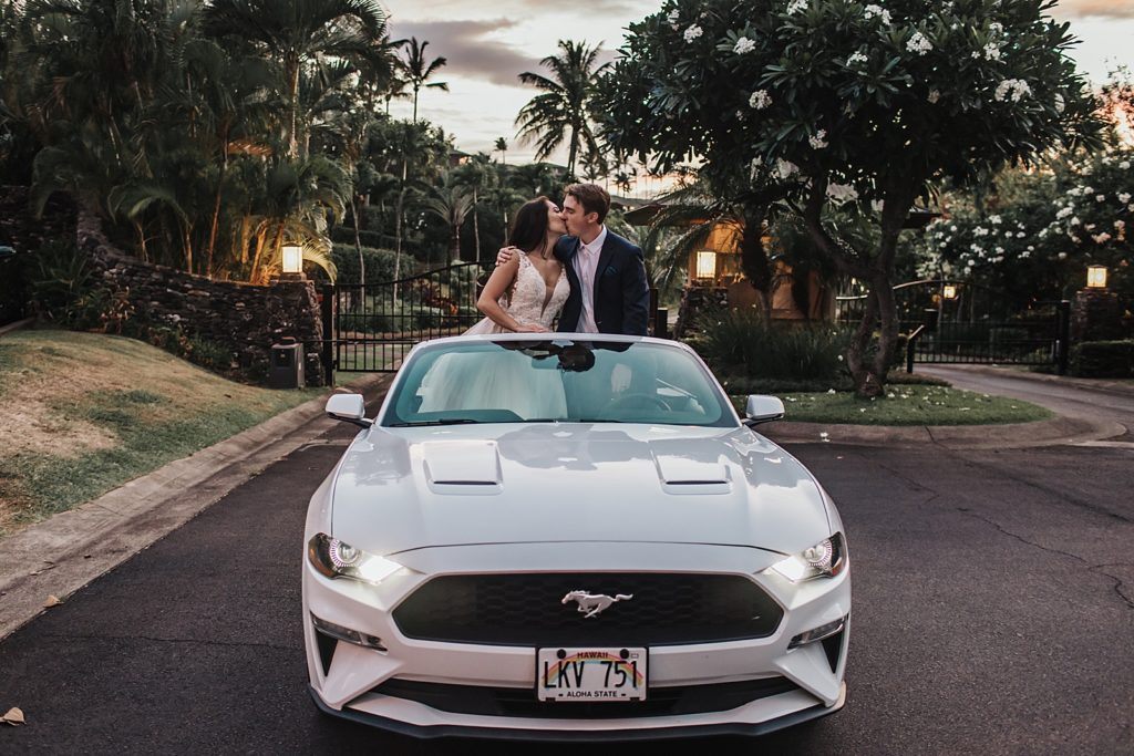 Bride and Groom kissing while standing in convertable charger car