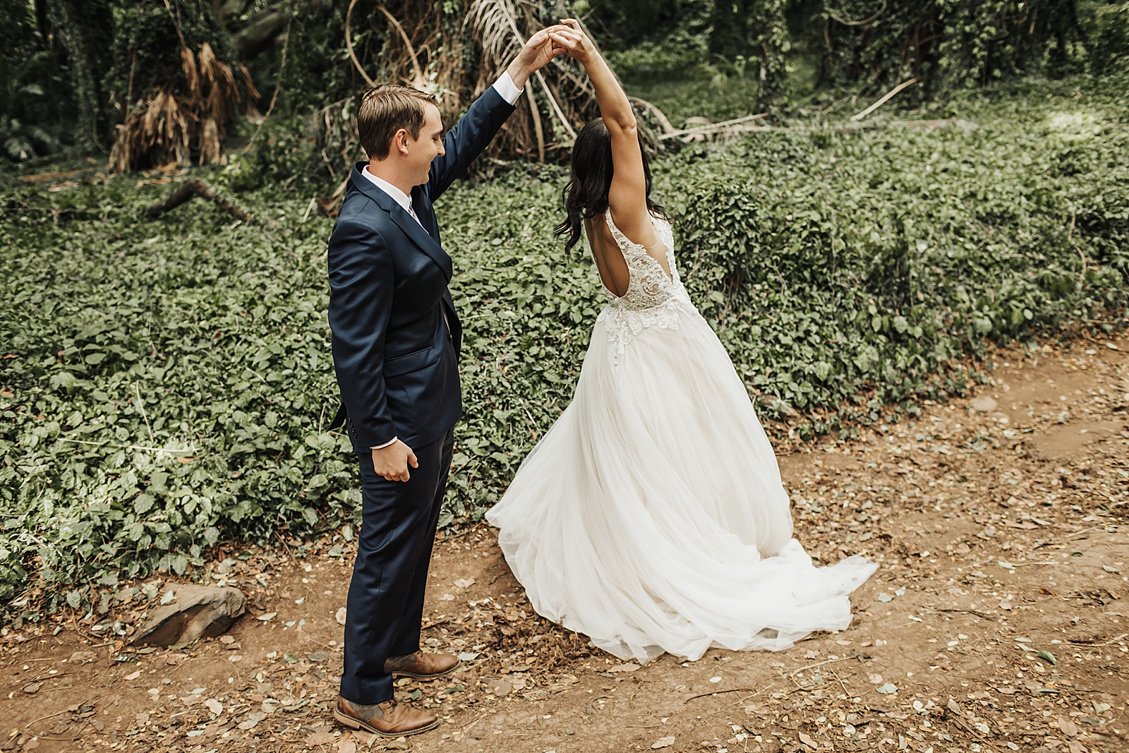 Bride twirling by Groom's hand by greenery