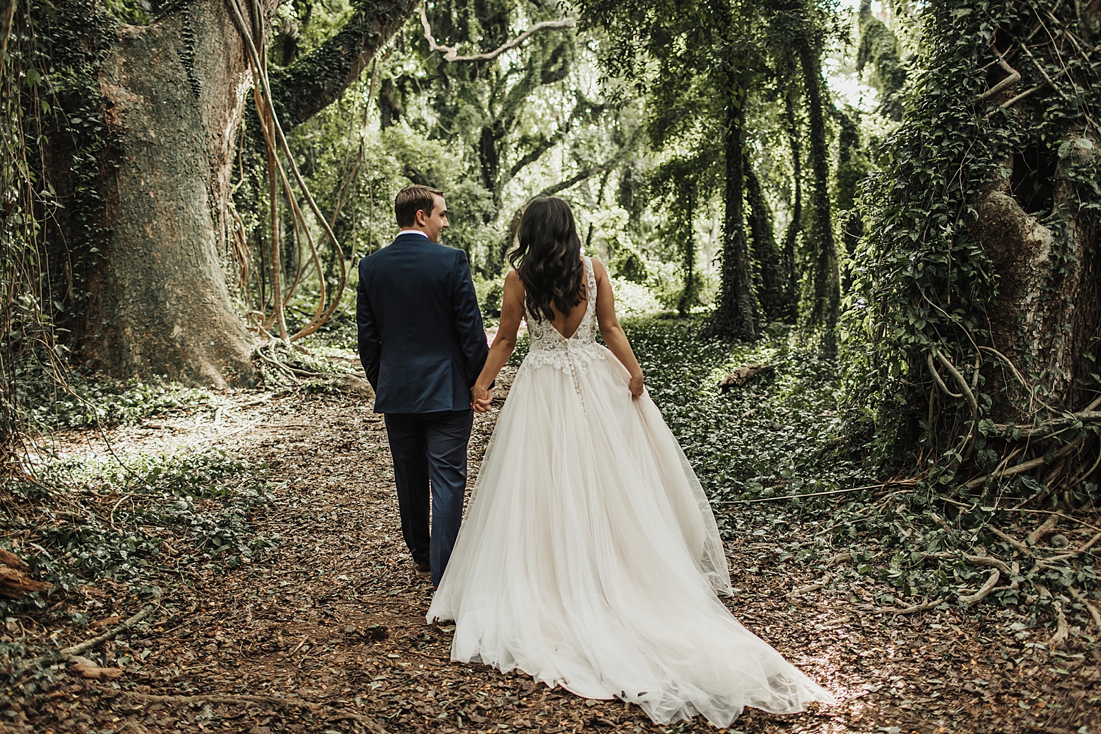 Bride and Groom holding hands and walking in forest together