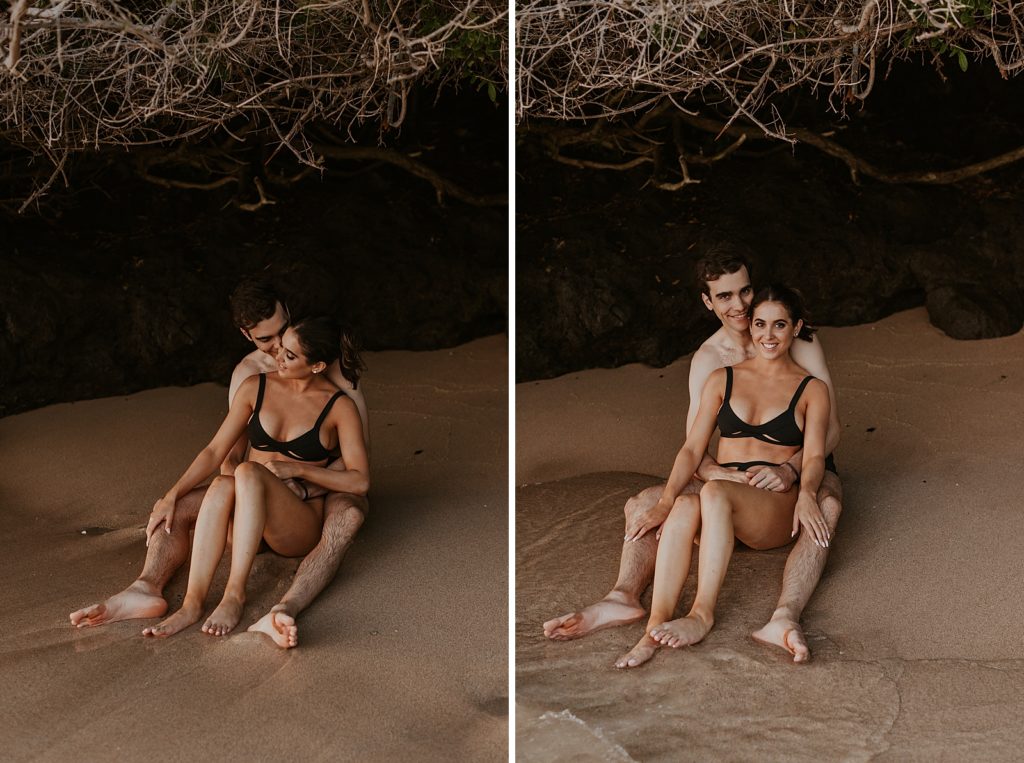 Woman sitting in man's lap while on the sand under land cover