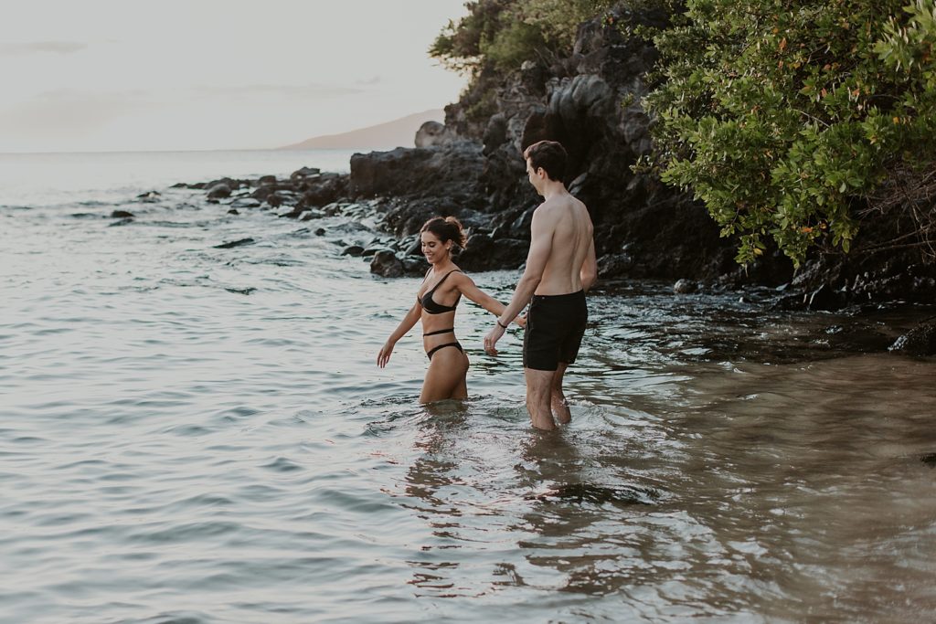 Woman holding man's hand and leading him into ocean water together