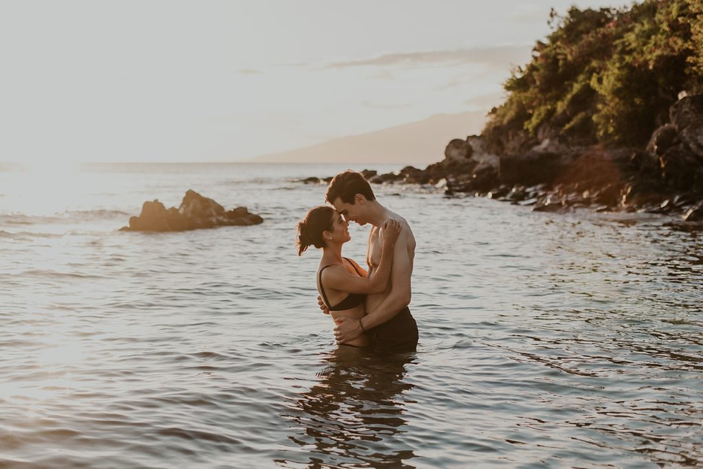 Couple looking at each other and touching noses knee deep in the ocean