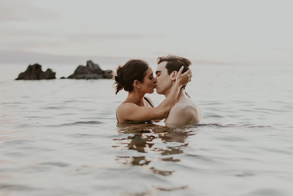 Couple kissing while shoulder deep in ocean water
