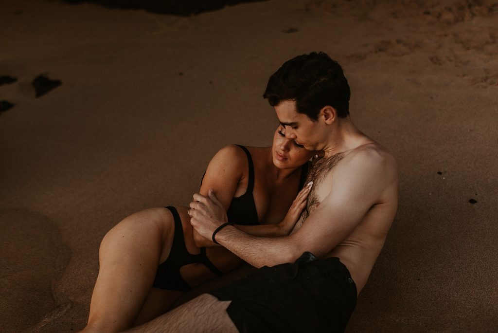 Couple laying in sand together and cuddling