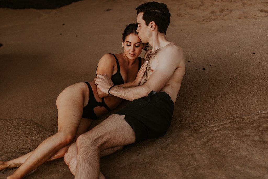 Couple laying in sand together and cuddling
