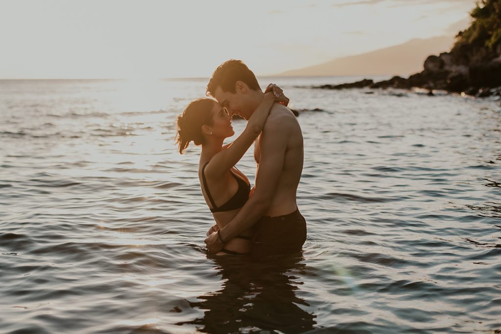Couple looking at each other and touching noses waist deep in the ocean