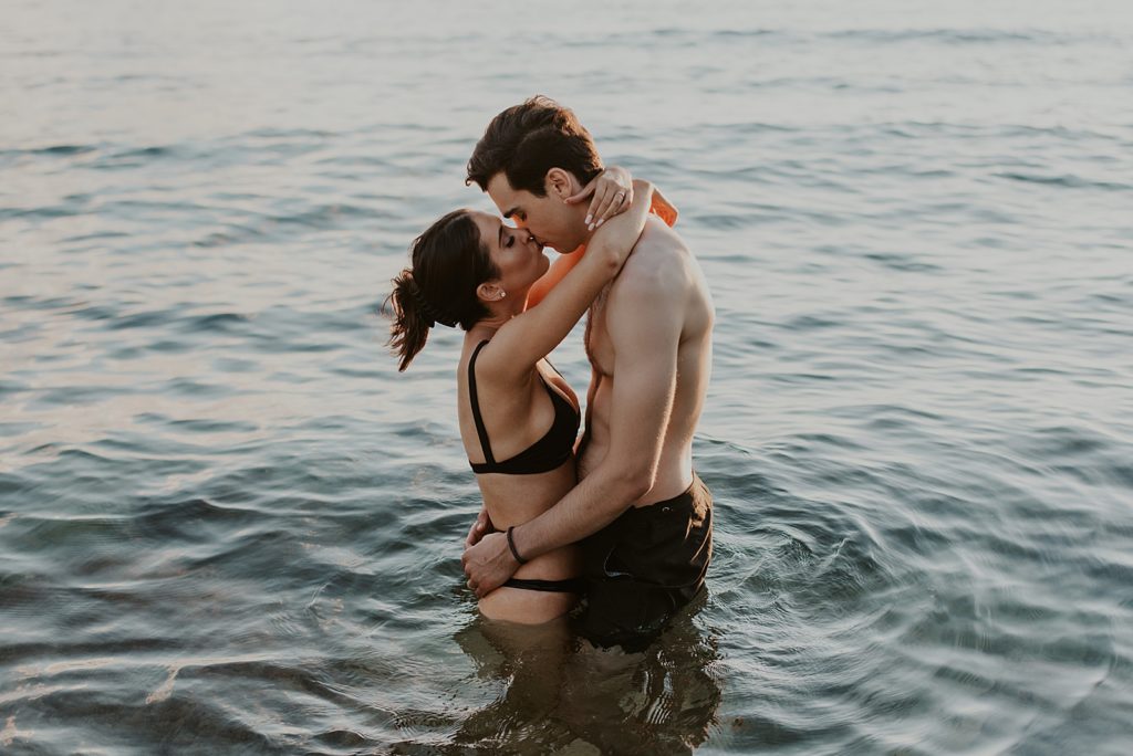 Couple holding each other and kissing waist deep in the ocean