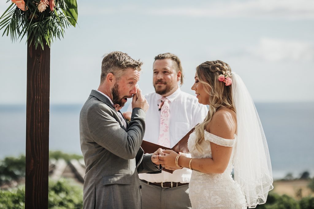 Groom tearing up during outdoor Ceremony with Bride holding hands