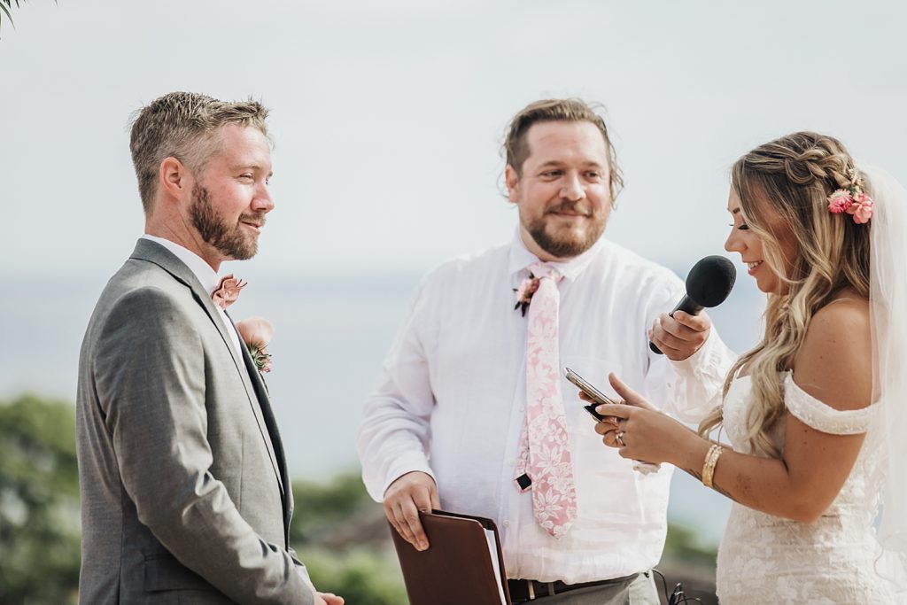 Bride giving vows to Groom with officiant holding microphone for outdoor Ceremony