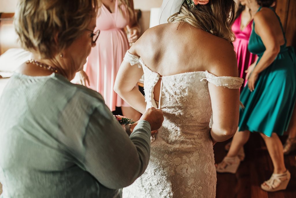 Mother helping Bride get dress zipped up getting ready