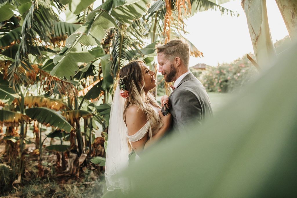 Bride and Groom looking at each other next to tropical greenery