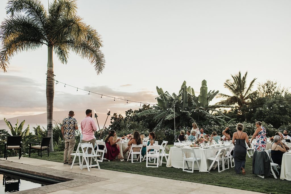 Wide shot of outdoor reception with white chairs and tables 