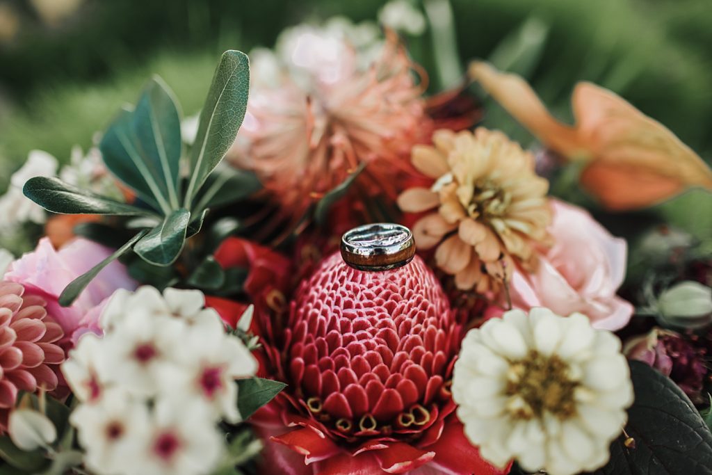 Detail shot of wedding band with tropical bouquet